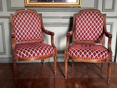 une paire de fauteuils rembourrés rouges placés devant un tableau accroché au mur
