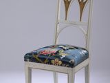 une image représentant une chaise blanche avec une assise bleue et un revêtement à motifs floraux