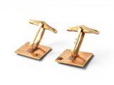 two pairs of gold colored cufflinks on a white surface