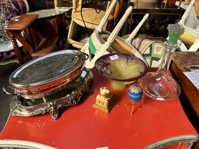 une table rouge sur laquelle se trouvent un bol de nourriture et une poêle en argent posée dessus