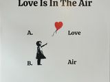 a sign that says love is in the air with a girl holding a red balloon