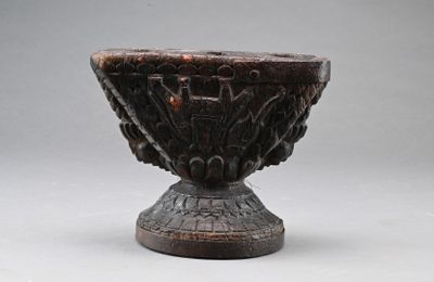 un bol en bois orné de sculptures, posé sur une table