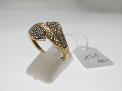 gros plan d'une bague en or avec des diamants sur une surface blanche