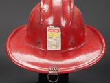 a red fireman ' s hat sitting on a black stand