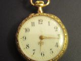 a close up of a gold pocket watch on a black surface