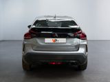 the rear end of a silver car in a room with a white wall
