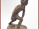 statue en bronze représentant un jeune garçon agenouillé sur un socle, tenant une raquette de tennis