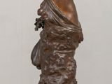 bronze statue of a woman holding a bird on a wooden table