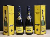 trois bouteilles de champagne posées sur une table, à côté d'une boîte