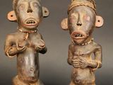 deux statues en bois représentant deux hommes coiffés d'un chapeau