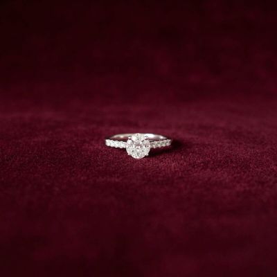 a close up of a diamond engagement ring on a red velvet background
