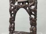 un vieux cadre en bois orné de sculptures, exposé dans une vitrine transparente