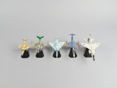 cinq avions en origami sont alignés sur une surface grise
