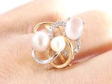 a close up of a person ' s hand holding a ring with pearls and diamonds