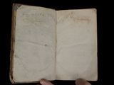 someone is holding an old book with writing on it in their hand