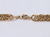 a close up of a gold chain bracelet on a white surface