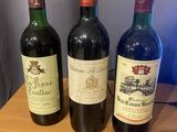 three bottles of wine are lined up on a wooden table