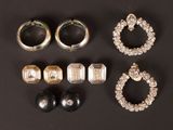 three pairs of earrings and a ring on a black surface