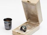 une bague dans une boîte en bois à côté d'une tasse