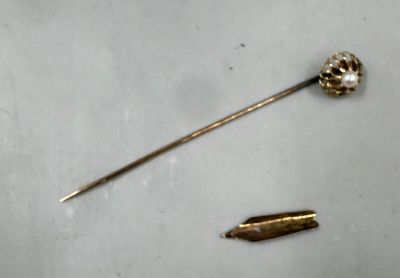 an image of a gold pin and a bullet on a white surface