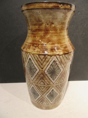 a brown and white vase sitting on a white table