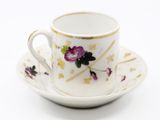 a white cup and saucer with purple flowers on it