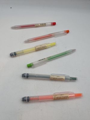 Plusieurs stylos de différentes couleurs sont alignés sur une surface blanche.