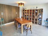 a room with a table, chairs, shelves, and bottles of wine