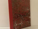 Le livre est posé sur une surface blanche et présente une couverture rouge.