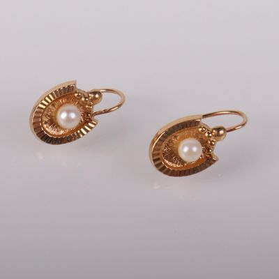 une paire de boucles d'oreilles en or ornées de perles sur fond blanc