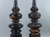 pair of black and gold candlesticks on pedestals against a gray background
