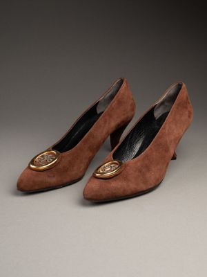une paire de chaussures en daim marron avec une boucle dorée au talon