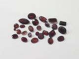 a close up of a bunch of red garnets on a white surface