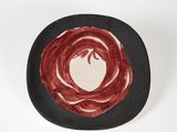une assiette noire ornée d'un motif rouge et blanc