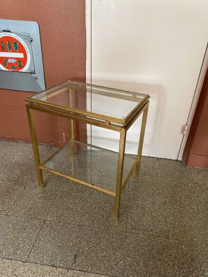 une table en verre avec un cadre doré et une pancarte posée dessus