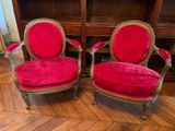 une paire de fauteuils en velours rouge avec des bordures dorées et des pieds en bois