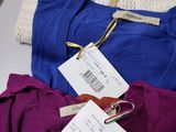 three pairs of sweaters with price tags on them sitting on a table
