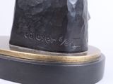 statue of a man with a hat on his head on a wooden base