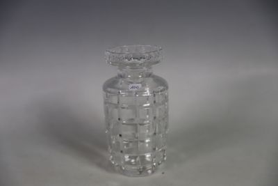 une petite bouteille en verre transparent avec un bouchon, posée sur une surface blanche