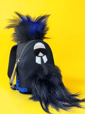 the small black bag has a furry animal on it ' s side
