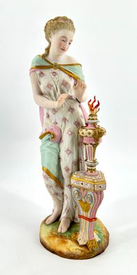 a figurine of a woman standing next to a vase
