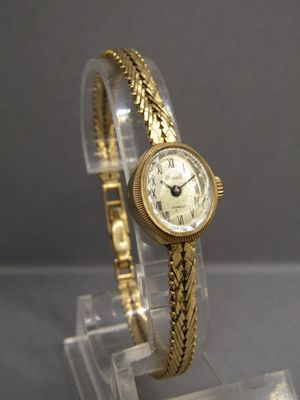 une montre-bracelet en or posée sur un présentoir transparent