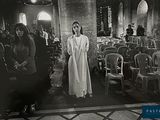 black and white photograph of a woman standing in a church surrounded by people