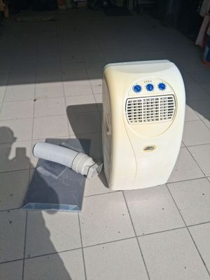 un petit climatiseur posé par terre à côté d'un rouleau de papier toilette