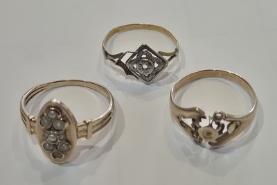 trois bagues ornées de diamants, posées sur une surface blanche