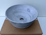 a gray bowl sitting on top of a cardboard box on a white surface