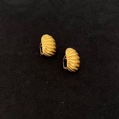 deux boucles d'oreilles dorées posées sur un fond noir