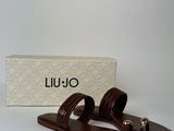 brown leather sandals with gold buckles and a box on a white surface