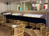 Des tables et des chaises sont disposées dans une salle, avec un bar en arrière-plan.