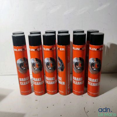 six bombes aérosols orange de nettoyant pour freins posées sur une surface blanche